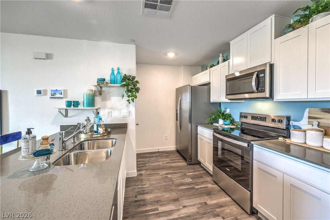 906 Pink Sugarbird Street, Henderson, NV 89011 Smooth stone countertops and white cabinetry anchor this functional culinary workspace.