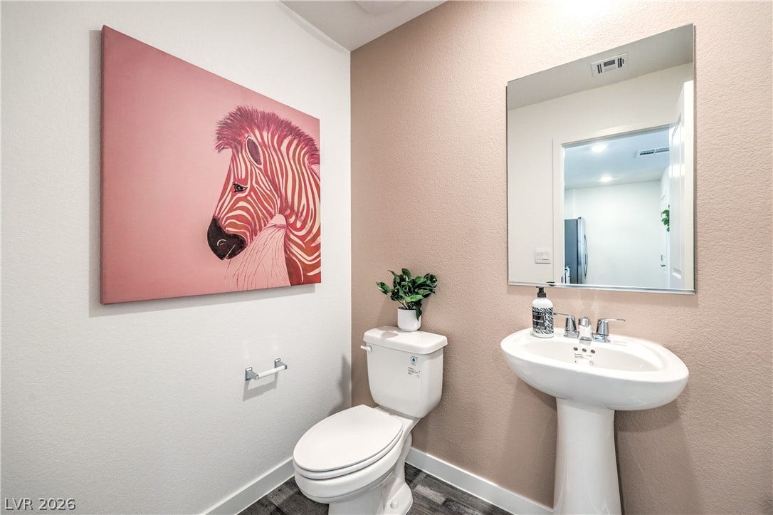 906 Pink Sugarbird Street, Henderson, NV 89011 Smooth plaster walls and dark flooring anchor this minimalist half bath.