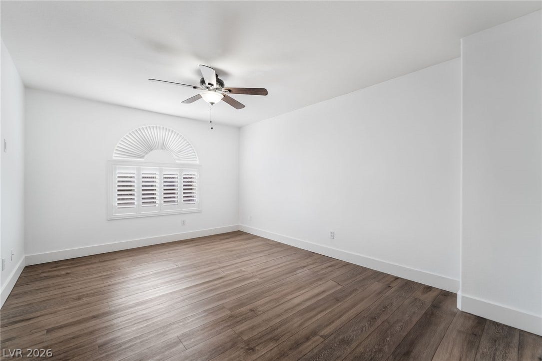 Rich wood-inspired flooring pairs beautifully with crisp white walls and a classic arched window.