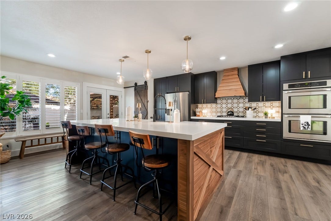 A spacious kitchen features dark cabinetry, modern appliances, and a wood-accented island.
