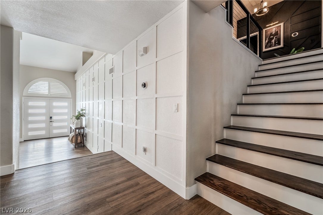 An elegant entryway welcomes guests with custom wall paneling and a modern staircase.