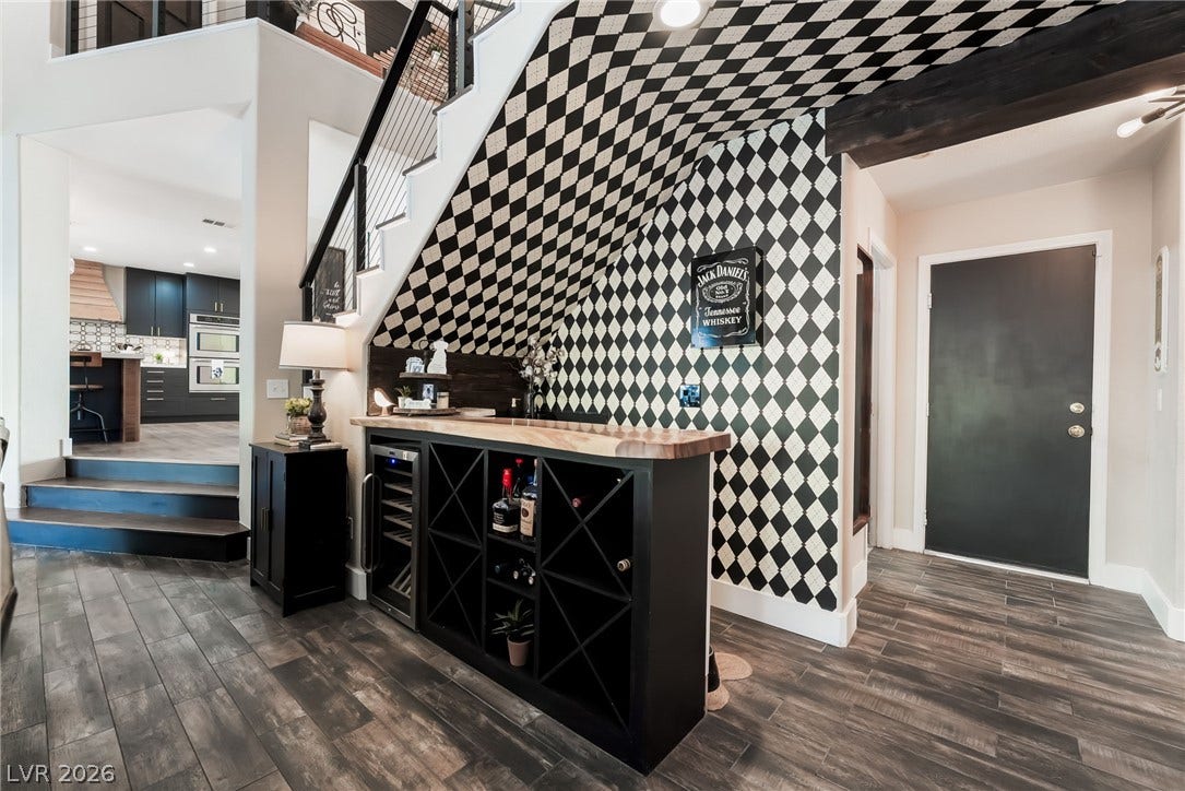An integrated bar area with a built-in wine cooler rests beneath the staircase.