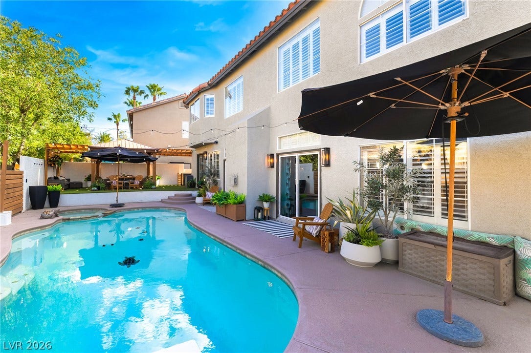 An inviting backyard oasis features a sparkling swimming pool, built-in spa, and concrete decking.