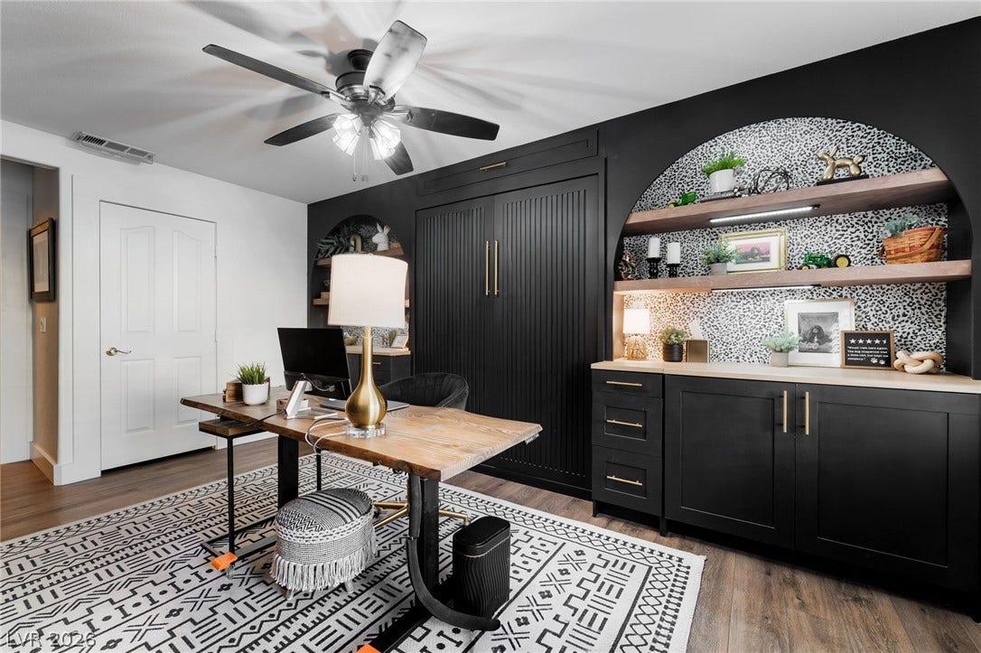 Custom built-ins and an arched alcove with shelving anchor this versatile home workspace.