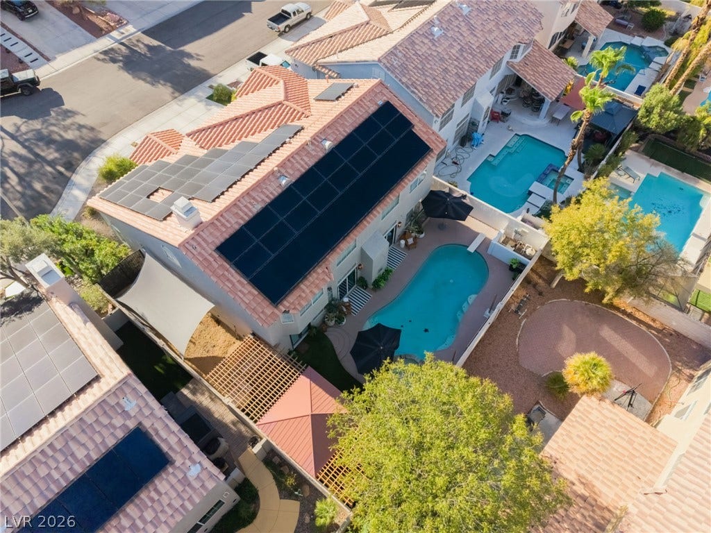 An aerial perspective showcases a backyard swimming pool paired with solar panels on the roof.