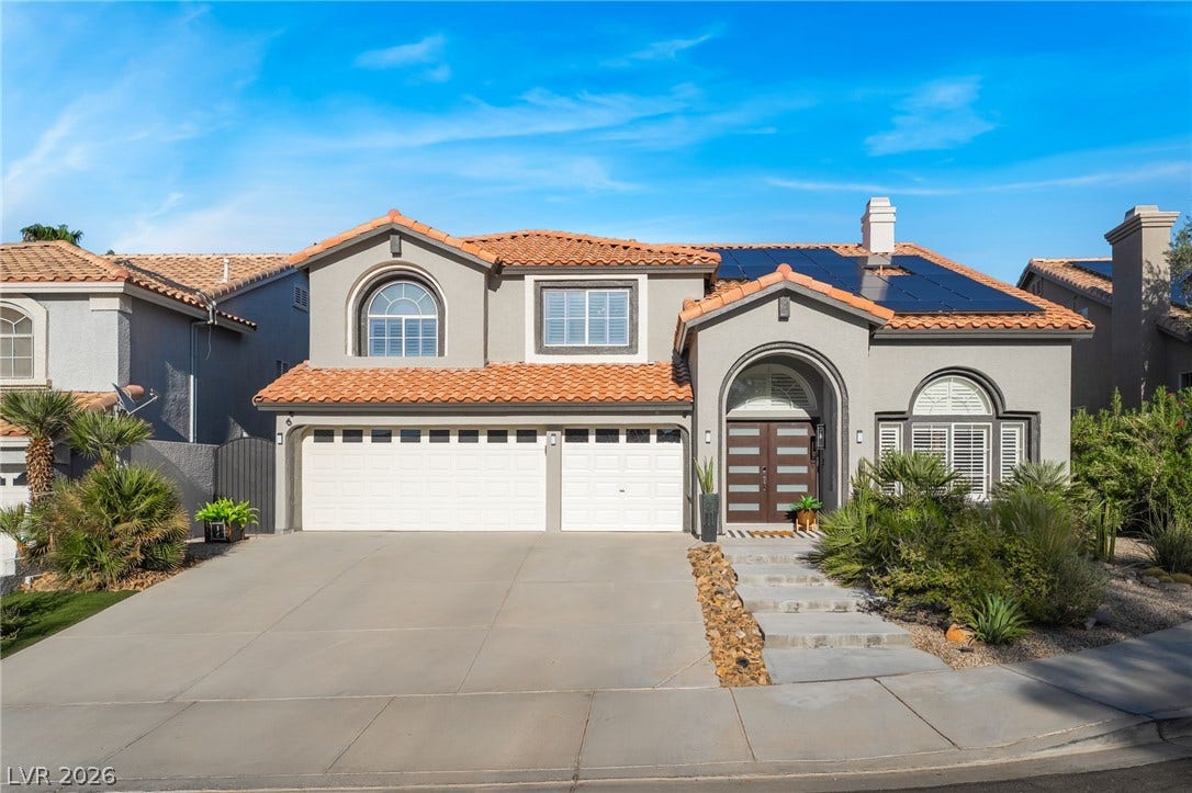 Spanish tile roofing and solar panels crown this classic stucco home with a wide driveway.