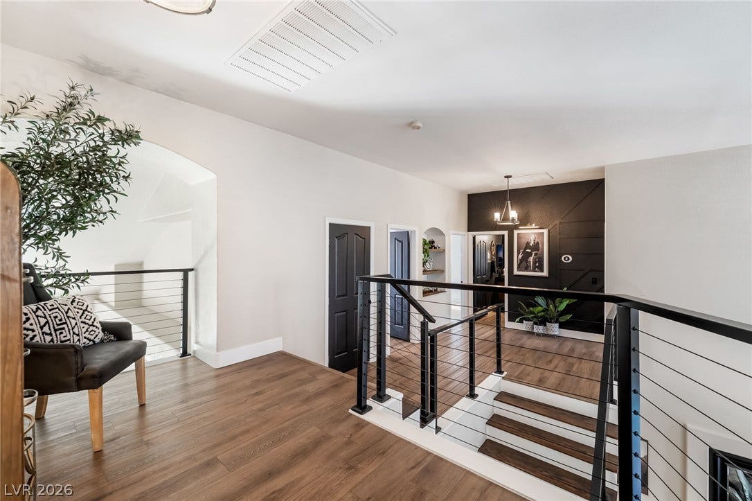 Rich wood floors and modern black metal railings line this spacious upper-level landing.