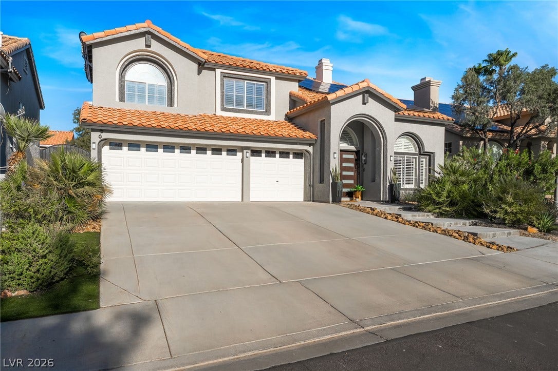 An arched entryway and Spanish tile roof highlight this elegant two-story stucco exterior.