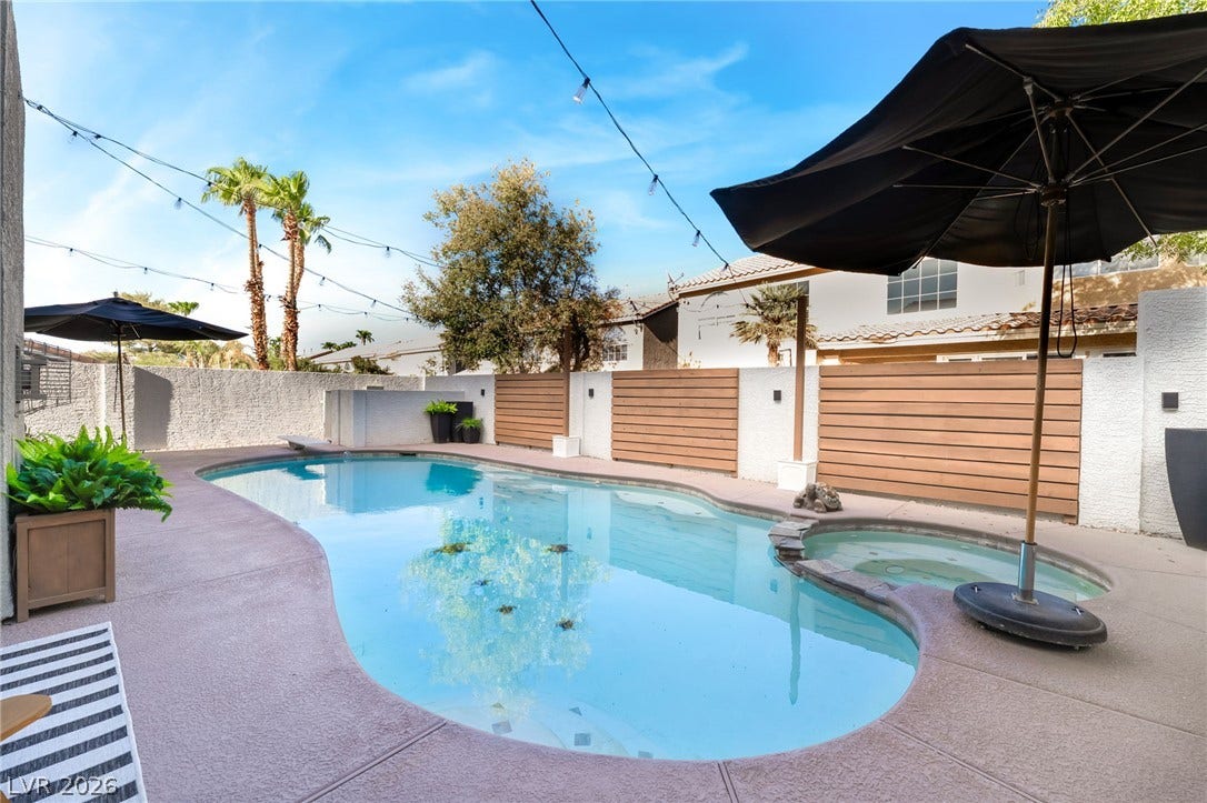 An inviting backyard oasis features a curved swimming pool integrated with an adjacent in-ground spa.