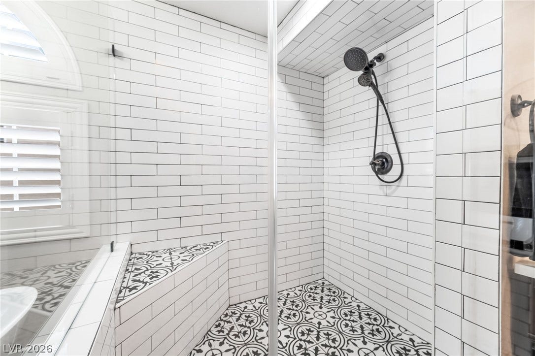 Patterned tile flooring and subway-tiled walls define this walk-in shower space.