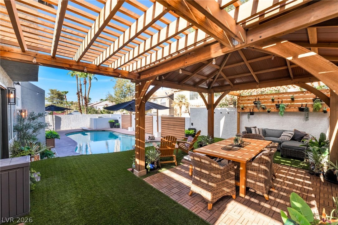 An inviting backyard oasis features a shaded wooden pavilion alongside a sparkling swimming pool.