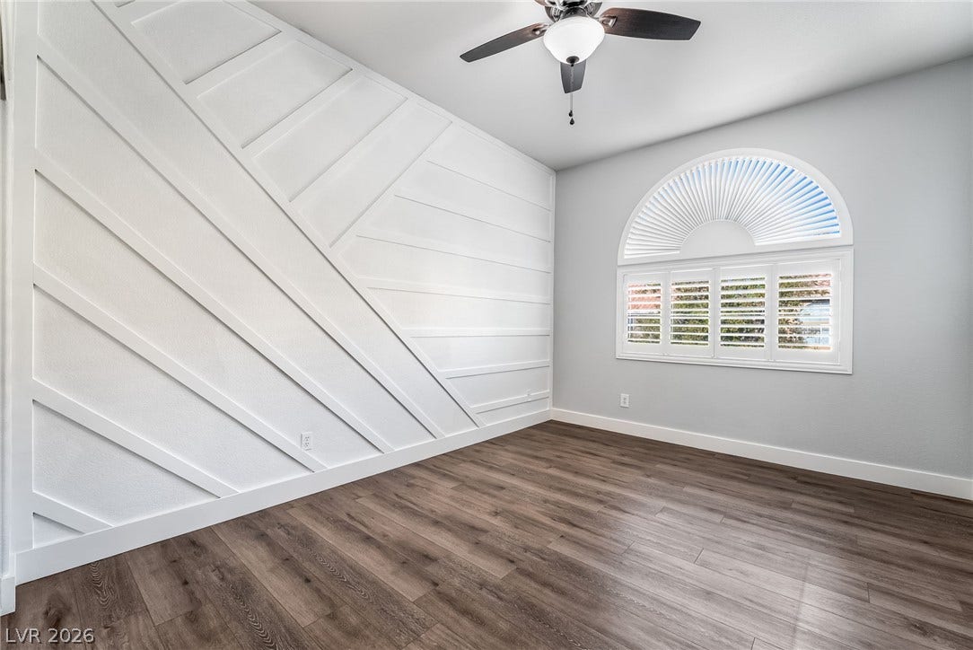 Geometric wall paneling and a large arched window create a stylish architectural focal point.