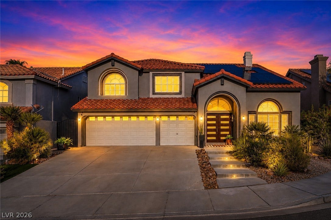 A spacious driveway leads to this multi-level home featuring arched windows and a clay tile roof.