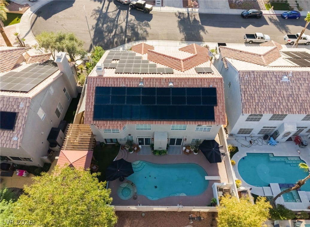 An aerial perspective captures the backyard swimming pool, patio area, and roof-mounted solar panels.