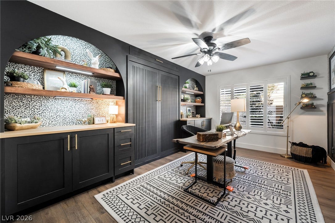 Custom arched built-ins and rich wood flooring define this versatile home workspace.