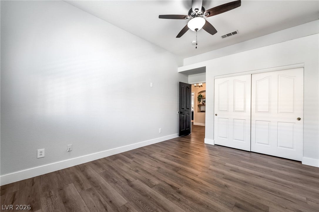 Rich wood-look flooring and crisp white trim define this versatile secondary room.