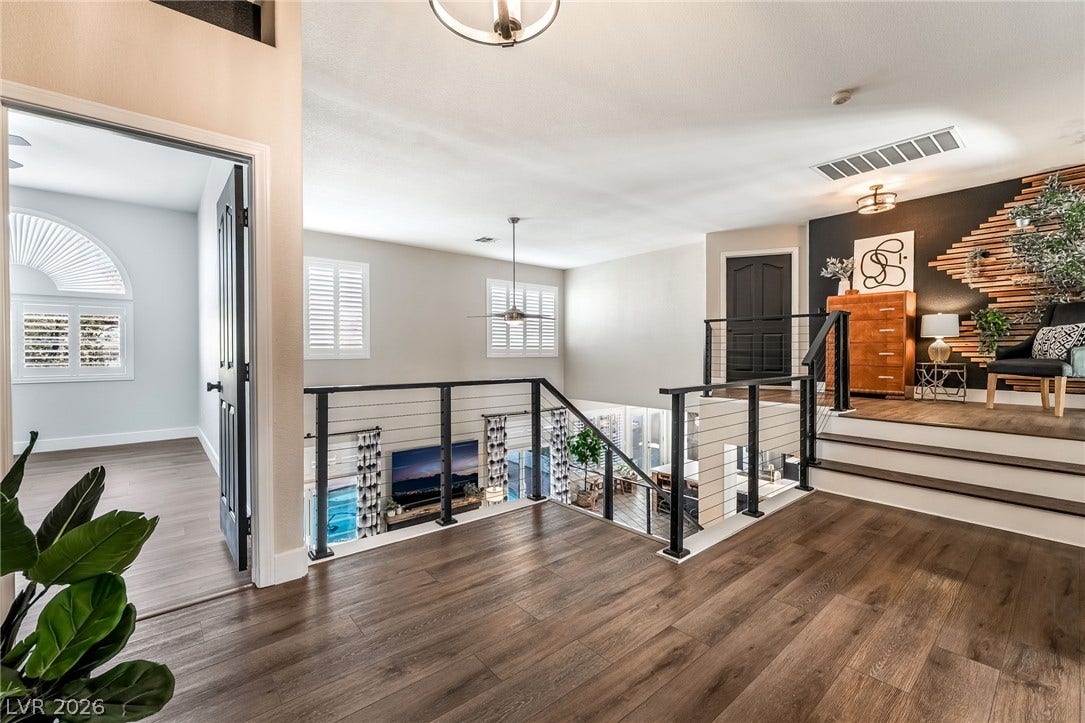 Rich wood-look flooring and modern horizontal cable railings define this multi-level upper landing.