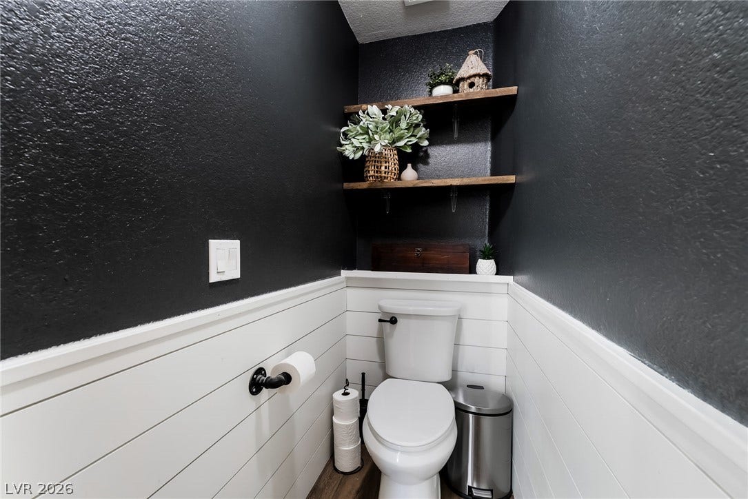 Crisp shiplap paneling and open wood shelving maximize storage and style in this powder room.