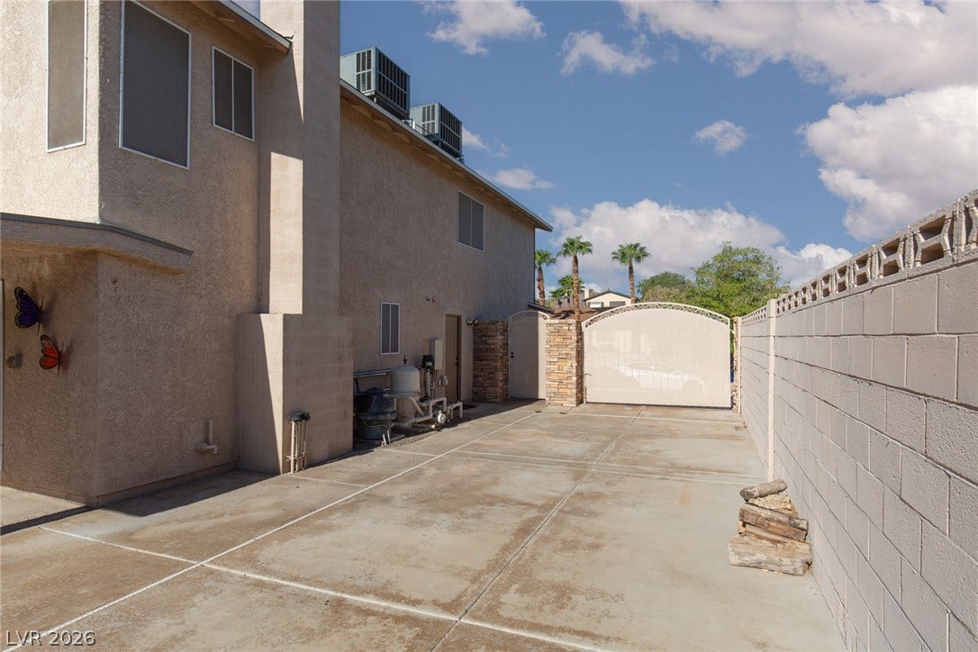 737 Brick Drive, Henderson, NV 89002 Concrete paving extends along the side yard bordered by a sturdy block wall and secure gate.
