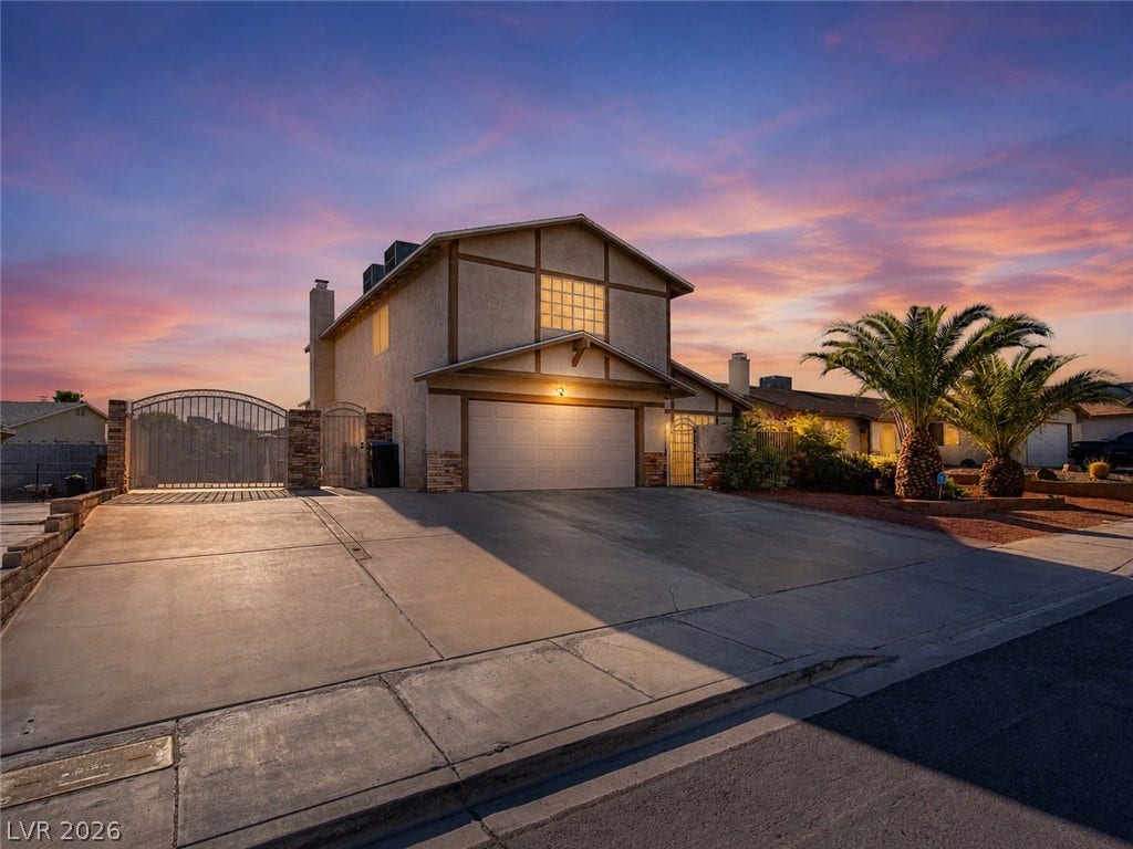 737 Brick Drive, Henderson, NV 89002 An expansive concrete driveway leads to a two-story home with integrated garage and security gate.