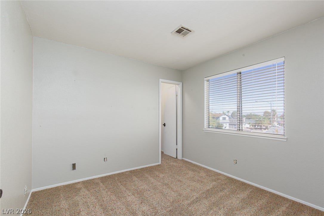 737 Brick Drive, Henderson, NV 89002 Soft carpeting pairs with a wide window overlooking the neighborhood in this cozy bedroom.