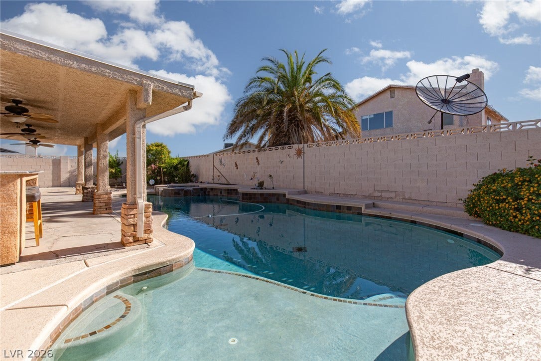 737 Brick Drive, Henderson, NV 89002 An inviting backyard features a curved swimming pool and a covered concrete patio.