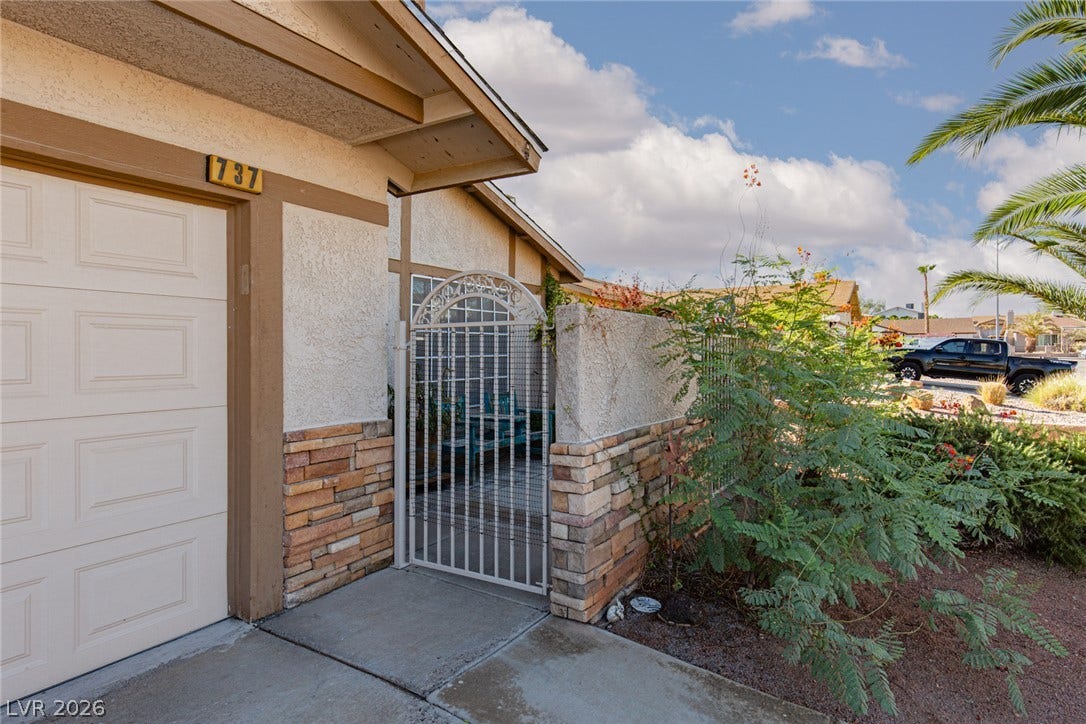 737 Brick Drive, Henderson, NV 89002 An arched iron gate opens to a private courtyard flanked by stone veneer accents.