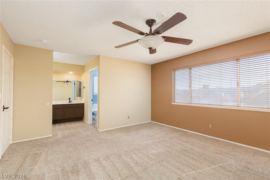 737 Brick Drive, Henderson, NV 89002 Plentiful natural light streams through wide windows, highlighting a spacious bedroom with an en suite vanity.