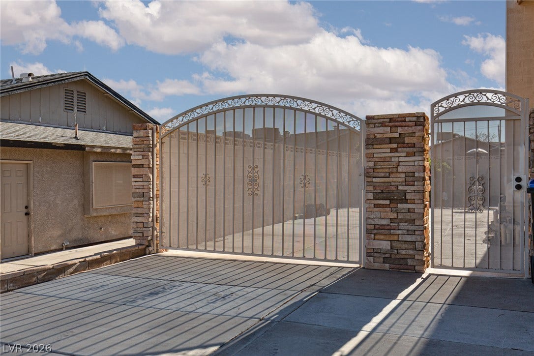 737 Brick Drive, Henderson, NV 89002 An arched security gate and brick pillars frame the paved driveway.