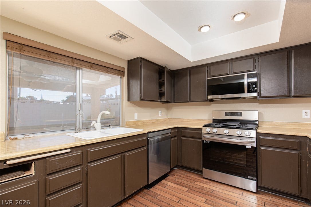 737 Brick Drive, Henderson, NV 89002 Rich wood-look flooring and dark cabinetry define this functional cooking space with stainless steel appliances.