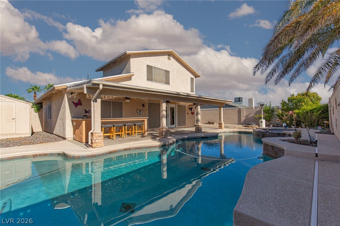 737 Brick Drive, Henderson, NV 89002 An inviting backyard oasis features a sparkling swimming pool beneath a covered patio.