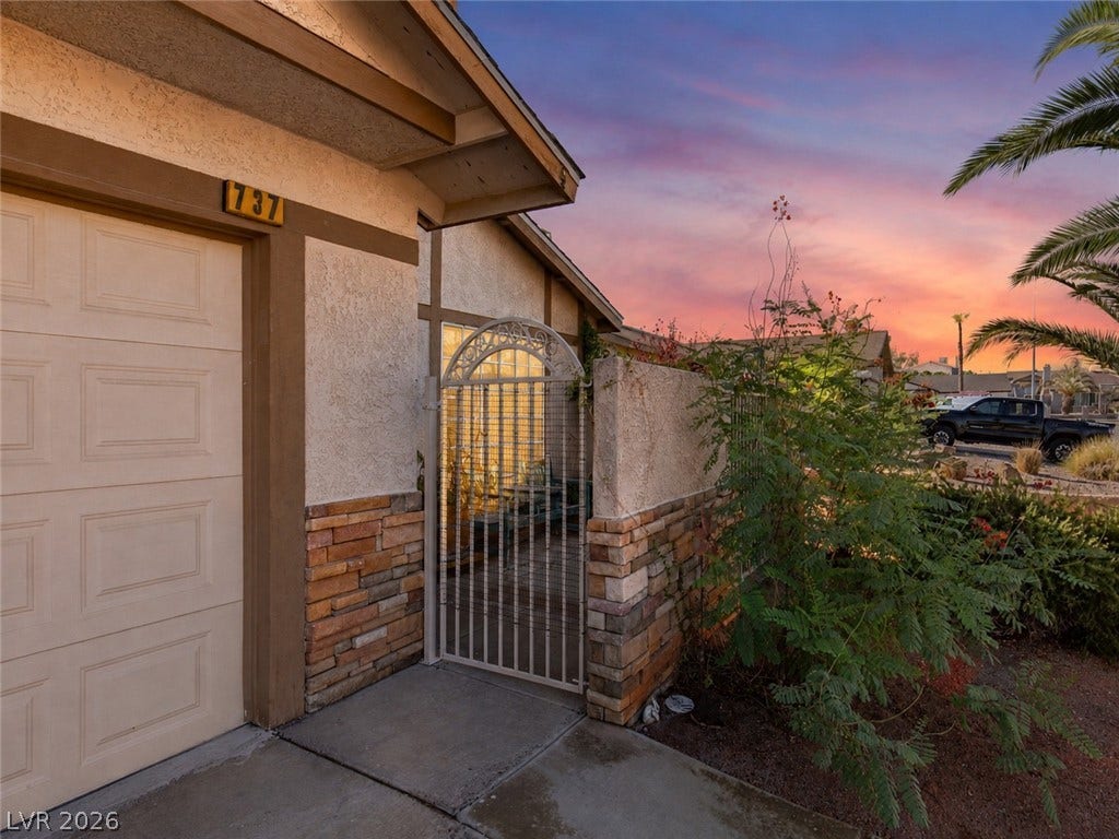 737 Brick Drive, Henderson, NV 89002 An arched wrought-iron gate secures the private entryway alongside a textured stone facade.