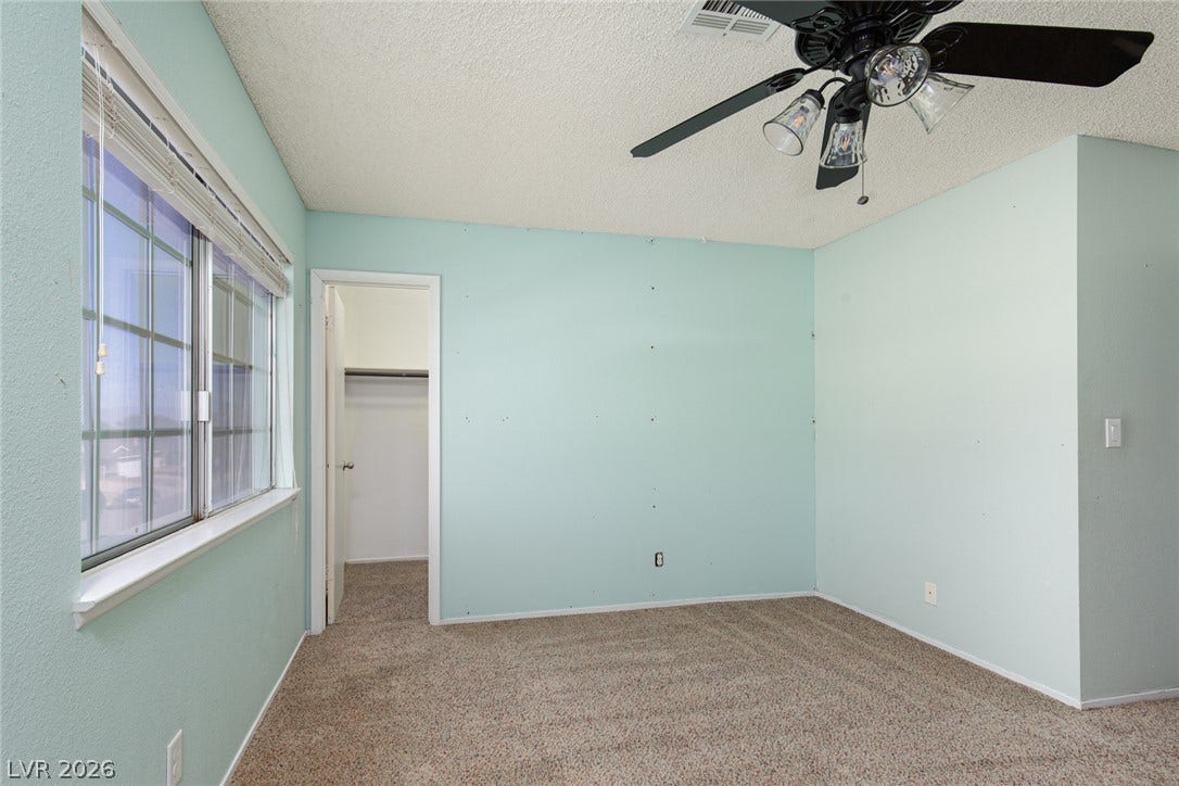 737 Brick Drive, Henderson, NV 89002 A spacious bedroom features neutral carpeting, a wide window, and an adjoining walk-in closet.