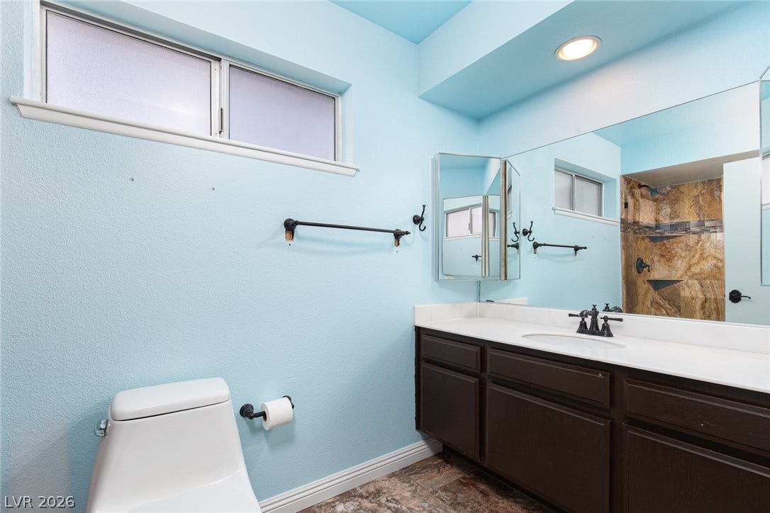 737 Brick Drive, Henderson, NV 89002 Textured stone-look flooring pairs with a dark wood vanity in this well-appointed bathroom.