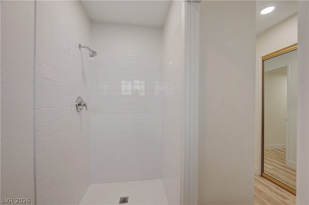 2101 Santiago Street, Las Vegas, NV 89104 A pristine tiled walk-in shower sits adjacent to a hallway featuring wood-style flooring.