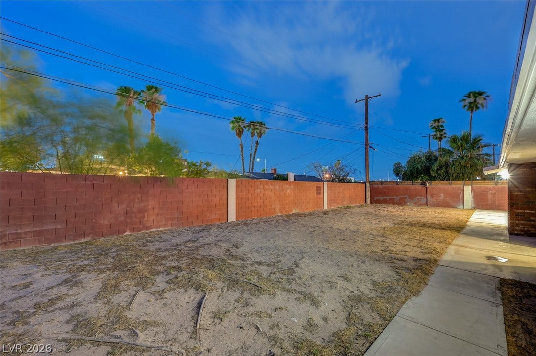 2101 Santiago Street, Las Vegas, NV 89104 Secure block fencing surrounds a spacious outdoor yard beneath a twilight sky.
