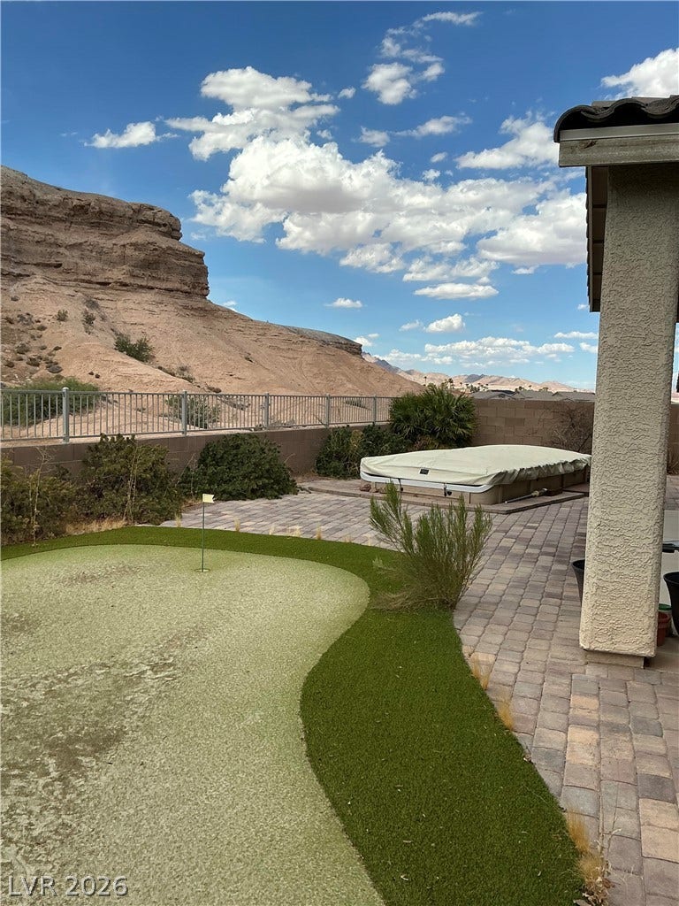 Dramatic desert cliffs create a breathtaking backdrop for the paved patio and putting green.