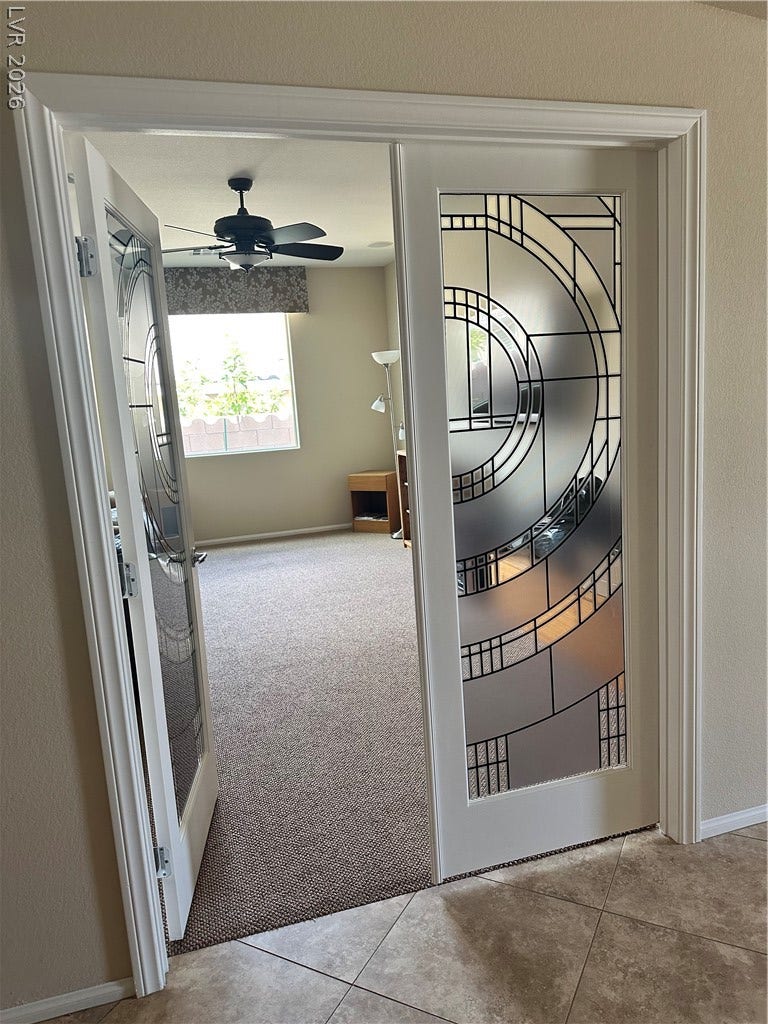 Double doors with leaded glass panels open into a versatile home office or den.