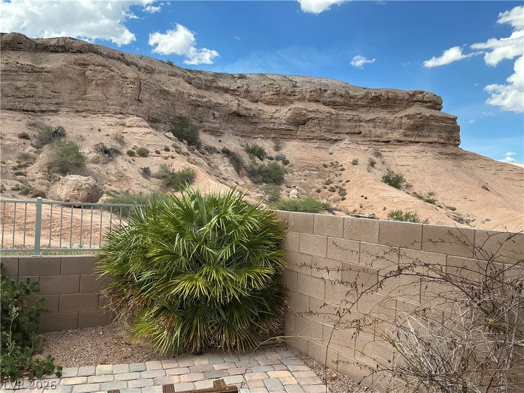 Dramatic canyon walls rise directly beyond the backyard stone pavers and block wall fencing.