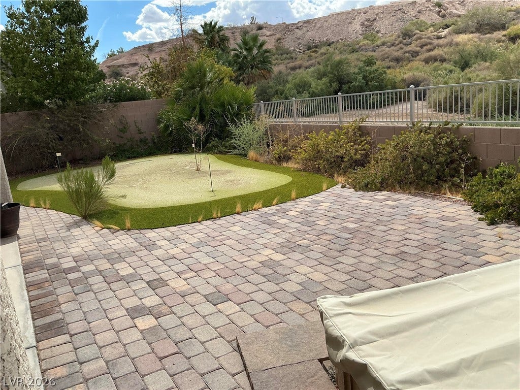 An inviting stone patio opens to a private putting green set against scenic desert hills.