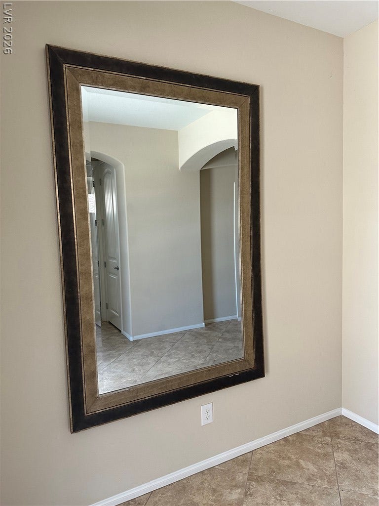 A spacious hallway features clean neutral walls and durable tile flooring.