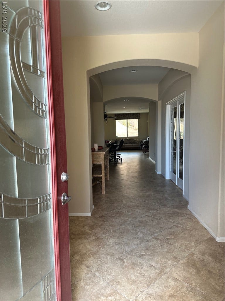 Arched transitions and tile flooring create an inviting entryway guiding guests into the main living areas.