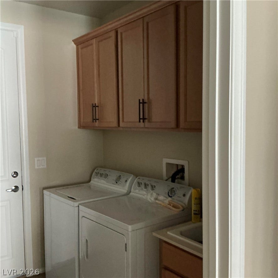 An organized utility space features overhead cabinetry, laundry hookups, and a built-in sink.