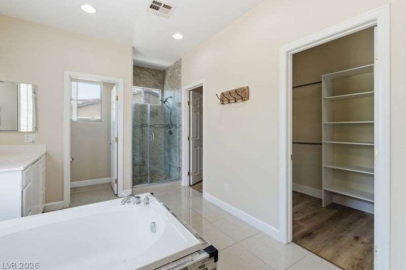 10464 Calico Pines Avenue, Las Vegas, NV 89135 A deep soaking tub sits adjacent to a generous walk-in closet with built-in shelving.