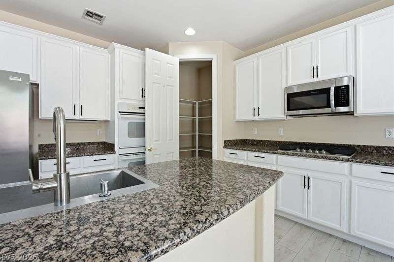 10464 Calico Pines Avenue, Las Vegas, NV 89135 Gleaming granite countertops pair beautifully with classic cabinetry in this open kitchen layout.