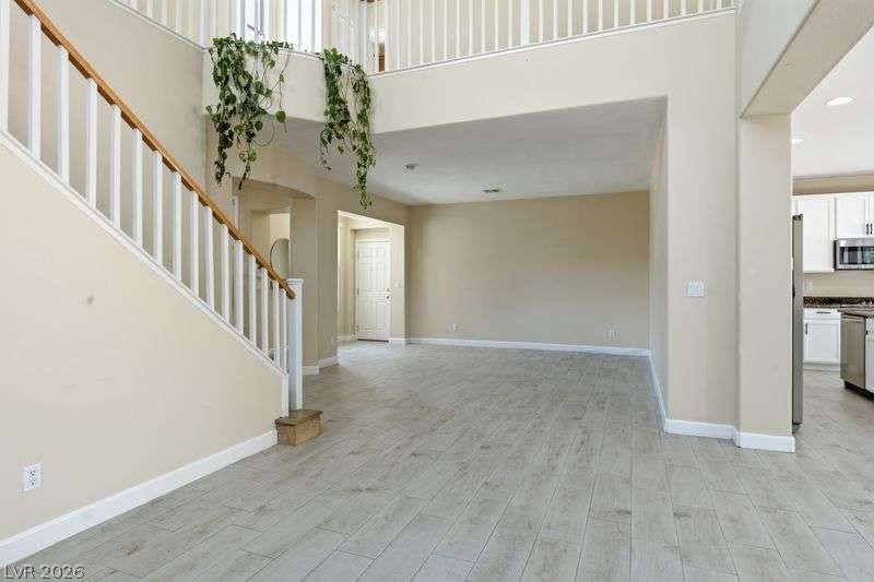 10464 Calico Pines Avenue, Las Vegas, NV 89135 Light-toned wood floors stretch across a spacious layout with high ceilings and a central staircase.