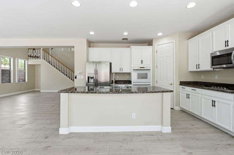10464 Calico Pines Avenue, Las Vegas, NV 89135 An open kitchen layout features rich stone countertops and sleek plank tile flooring.