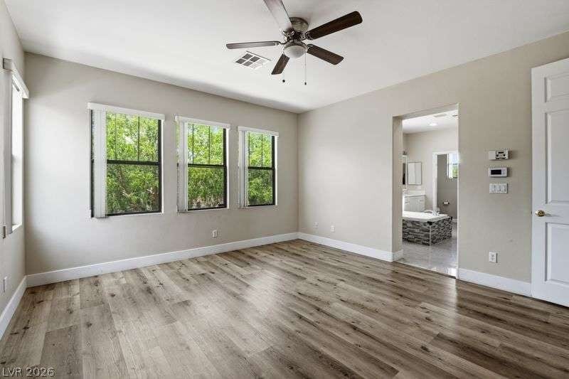 10464 Calico Pines Avenue, Las Vegas, NV 89135 Gleaming wood-look floors anchor this airy bedroom complete with wide windows looking out to nature.