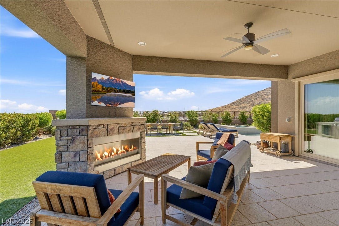 An inviting covered patio features a stone fireplace alongside scenic mountain views.