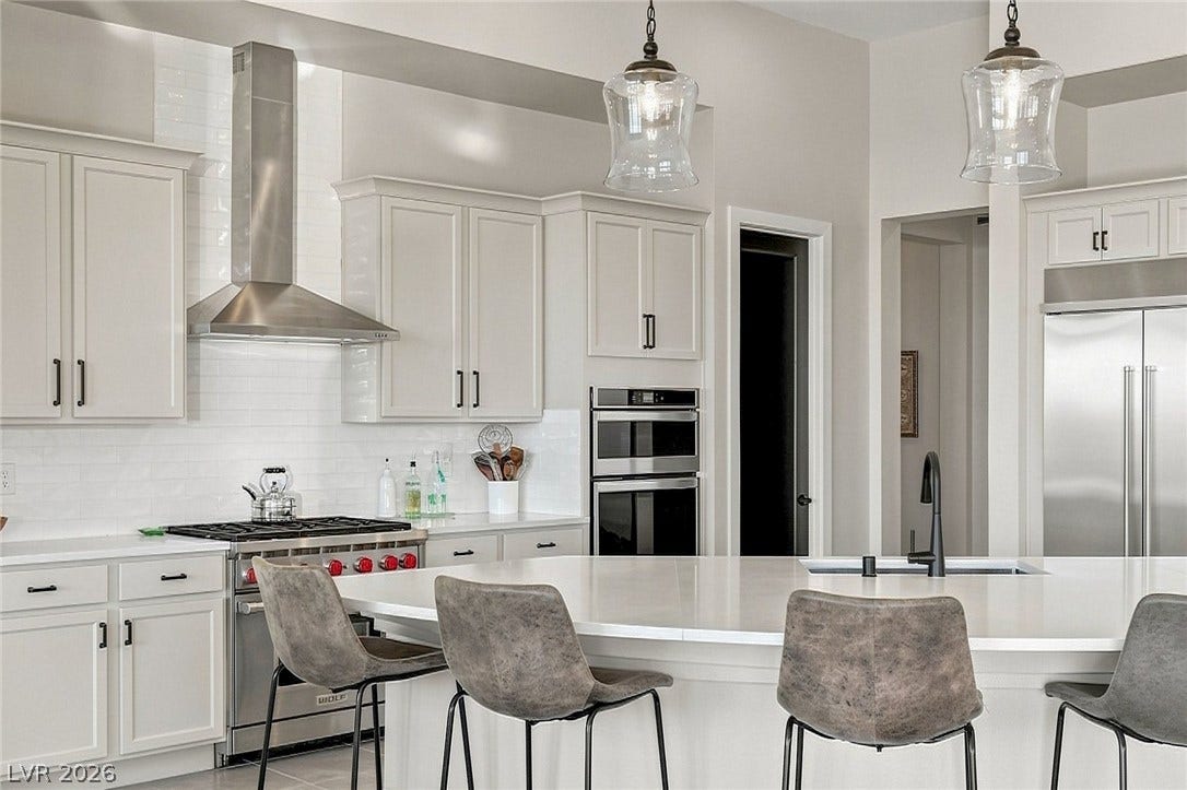 High ceilings and a generous island anchor this gourmet kitchen space which features Wolf range, built in premium finishes.